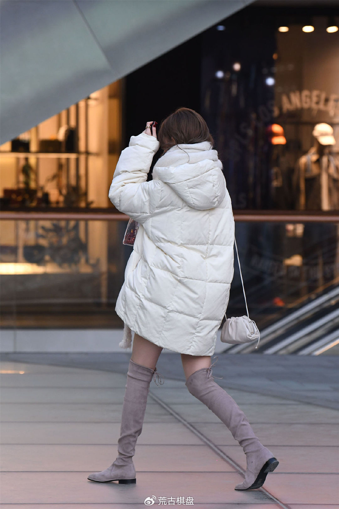 浅灰色的过膝靴,平底的款式,搭配超薄肉色丝袜,中款羽绒服