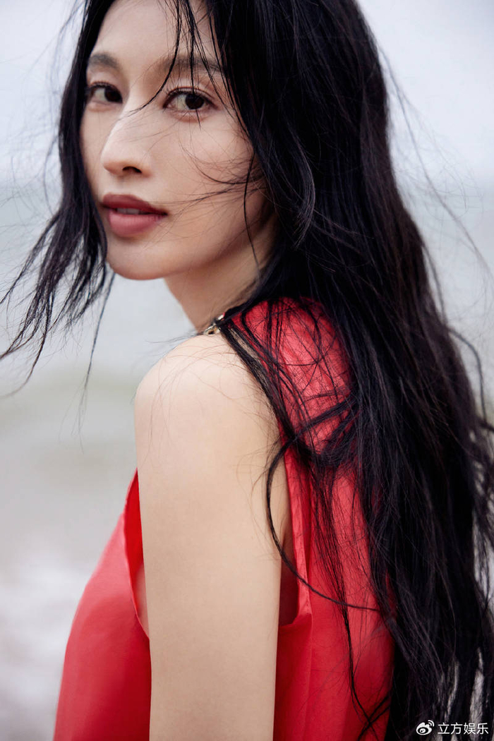 张俪穿红色长裙赤脚漫步海边 海风吹动长发回眸氛围感拉满