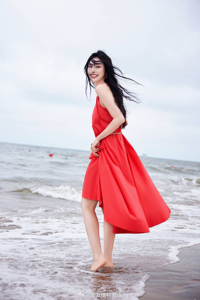 张俪穿红色长裙赤脚漫步海边 海风吹动长发回眸氛围感拉满