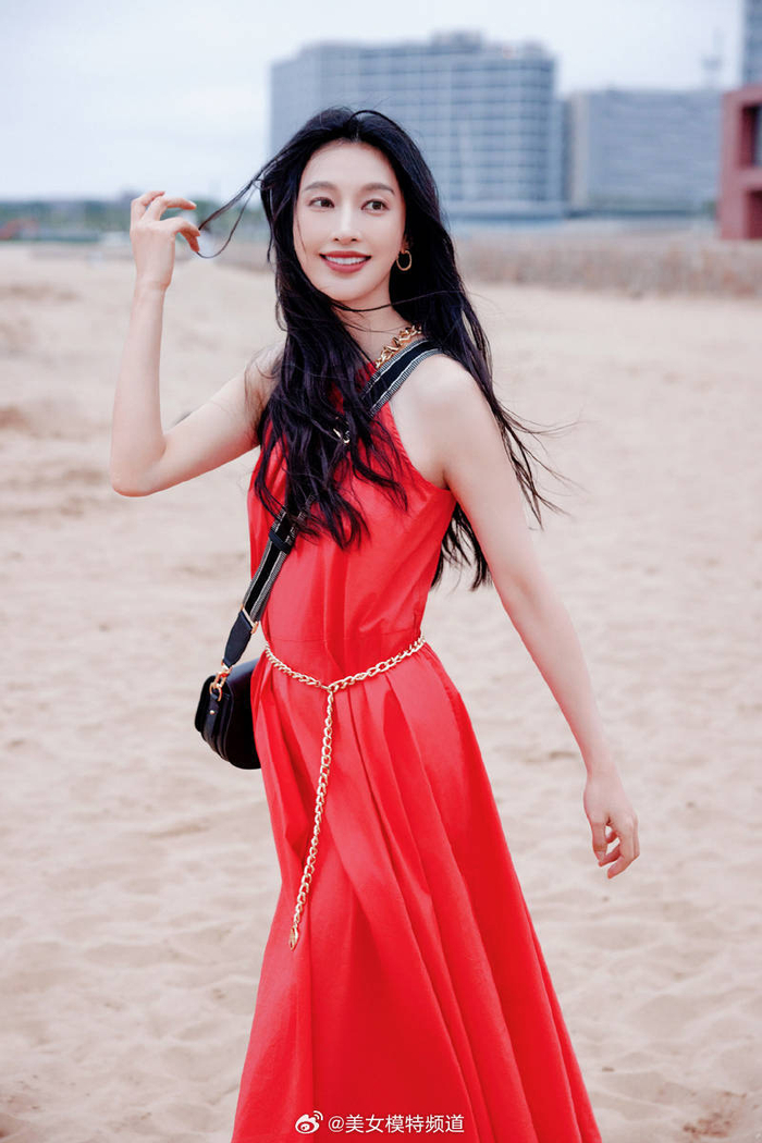张俪穿红色长裙赤脚漫步海边 海风吹动长发回眸氛围感拉满