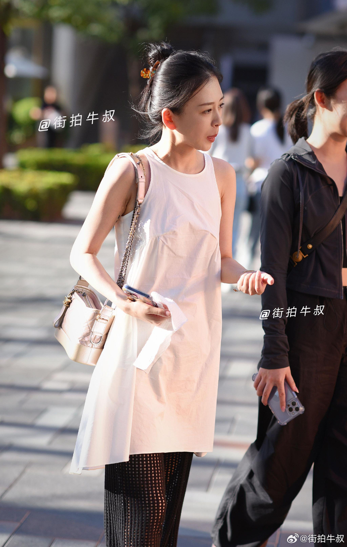美女穿着简约的白色无袖连衣裙出街