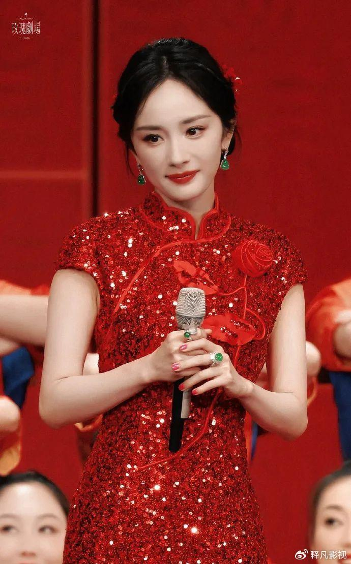 穿着传统的中国红无袖旗袍,双手拿着话筒,大秀曼妙的身材,杨幂微微