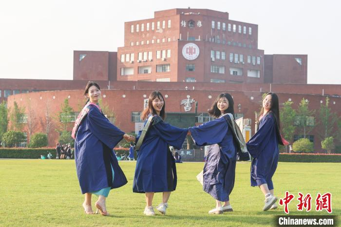 图为江西师范大学2024届毕业生身着学位服在校园内拍照留念.