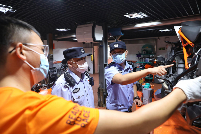 民警向机修师询问车辆情况。新京报记者 王飞 摄