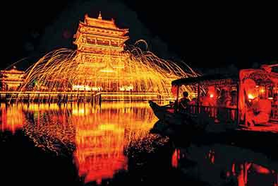 　　在台儿庄古城，游客坐在船上观看打钢花非遗表演（8月20日摄）。新华社记者郭绪雷摄