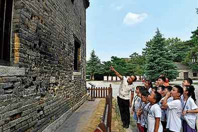 　　在台儿庄大战遗址公园弹孔墙前，作家时培京（左一）给孩子讲述历史（8月19日摄）。新华社记者郭绪雷摄