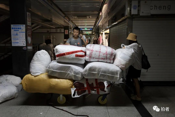 △&nbsp;9月26日，广州万佳服装批发市场，一名日卖两千件货的主播（右一）从阿燕的档口拿完货后，雇了一名搬运工帮忙运货。