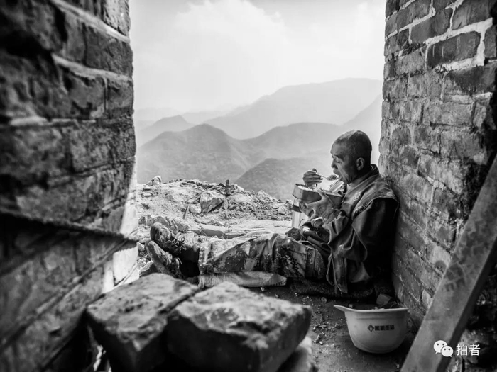 △ 9月26日，一位工人坐在90号敌台一角吃午饭。施工现场没有加热设备，工人早晨出门带上盒饭，中午就吃冷饭。