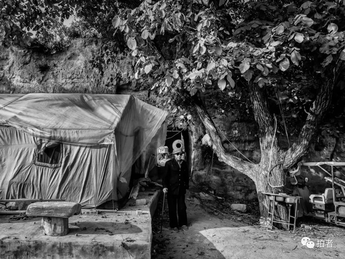 △ 9月26日，延庆区双营古城，一位老人站在自家院墙外。这段院墙也是明代土城墙，虽保存较完整，但墙头随处可见的植被根系已经完全深入墙体内。