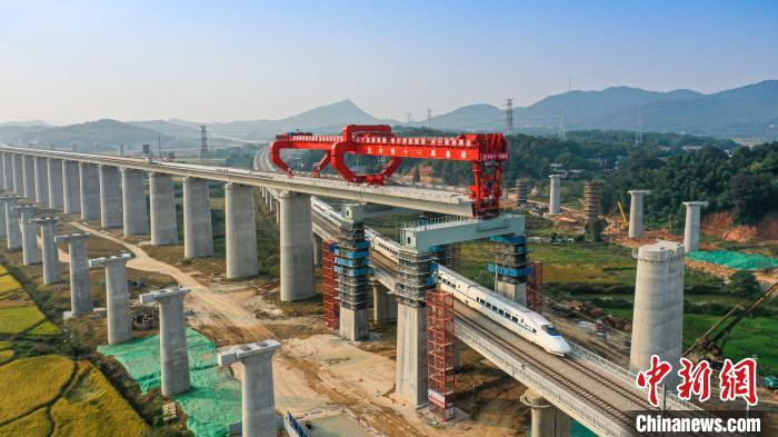     图为乌山联络线动车穿过正在架梁中的常益长高铁黄桥大道特大桥。　彭特　摄