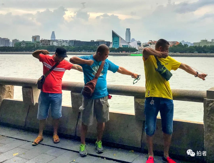 △ “弓友”。2016年7月18日，三位弓友一字排开，对着江面的漂浮物瞄准。近年来，孩童时代的玩具弹弓日渐成为都市成年人的一项爱好。一方面锻炼肌肉，舒筋活络，另一方面又能娱乐放松，结交朋友。