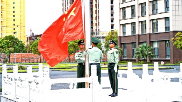 图说：鲜艳的五星红旗在两代军人的注视下冉冉升起。杨阔 王毅明 摄 （下同）