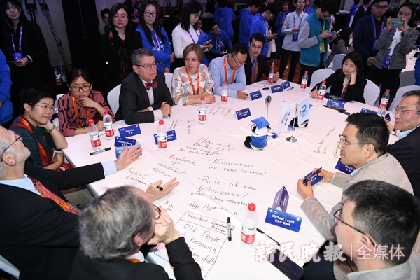 图说：顶尖科学家与青年科学家共同交流并在桌布上写下讨论的内容