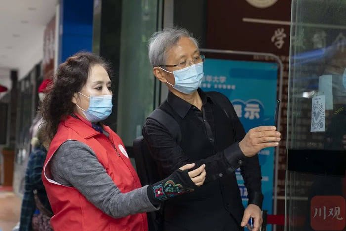  老年人在志愿者帮助下，扫描天府通健康码