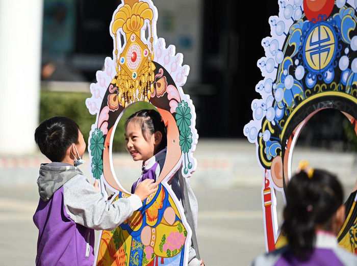 北京园博园内，小学生与戏曲卡通形象合影。摄影/新京报记者 陶冉