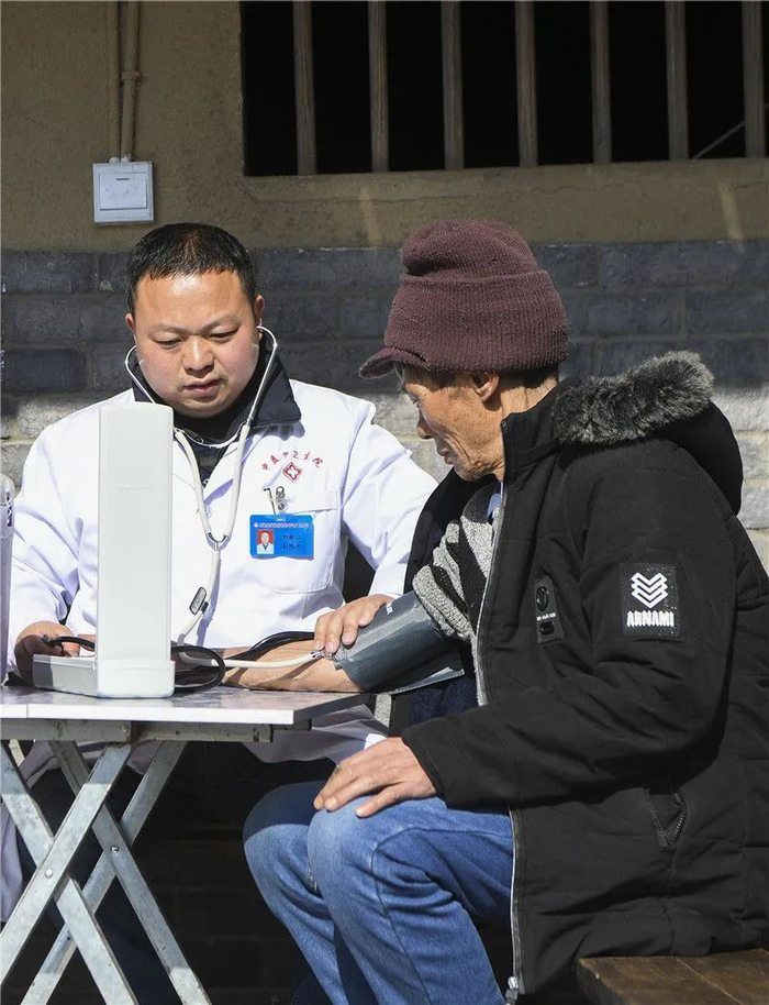 重庆石柱土家族自治县中益乡卫生院的医护人员为中益乡华溪村村民谭登周测量血压（2019年12月10日摄）。新华社记者 王全超 摄