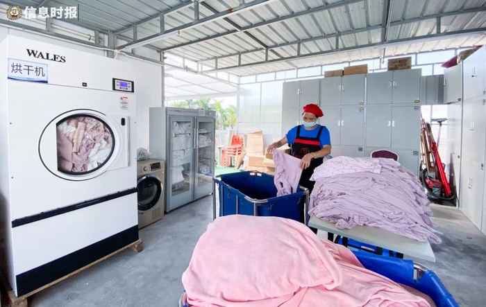得宝月子中心，工作人员进行被单衣物整理，旁边设有烘干机和紫外线消毒机。信息时报记者 徐敏 摄