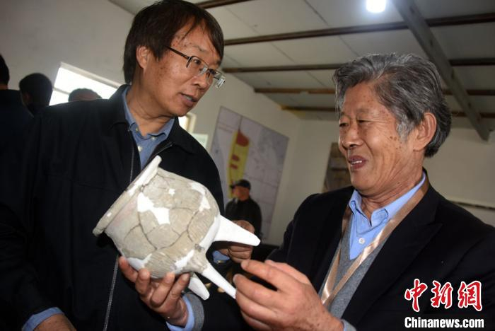 陈星灿研究员(左)与王吉怀研究员对遗址出土文物进行交流。　孙自法 摄