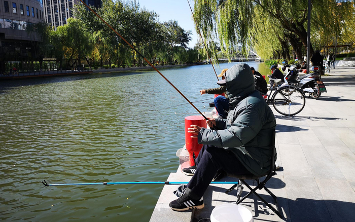 亮马河边有市民正在钓鱼。新京报记者 黄哲程 摄