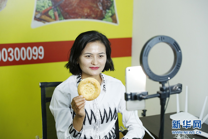 　　伽师县馕产业园工作人员利用网络直播销售果仁馕、辣皮子馕、小酥馕等馕产品。新华网记者 焦鹏 摄