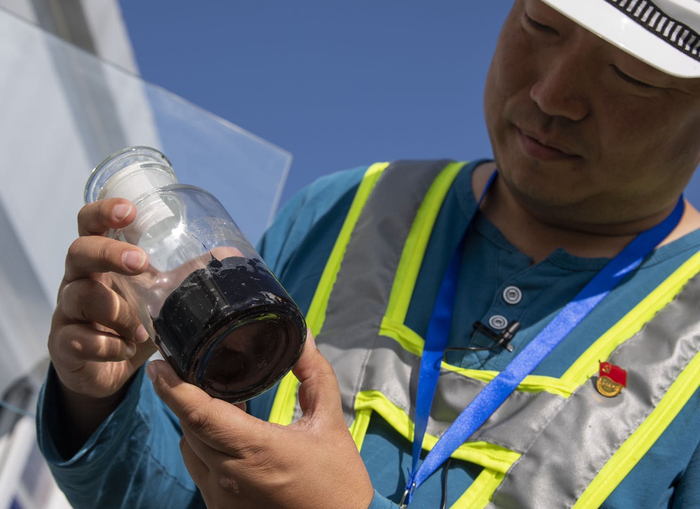 工程建设者曹承展示加在沥青中的材料。摄影/新京报记者 陶冉