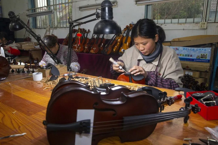 ▲2019年12月17日，在江苏泰州黄桥镇凤灵乐器集团，工人在车间对提琴进行上腮托。图/视觉中国
