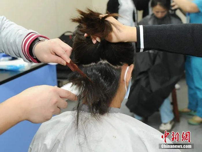 图为吉林援鄂医疗队出征湖北前医护人员剪掉长发。刘栋 摄