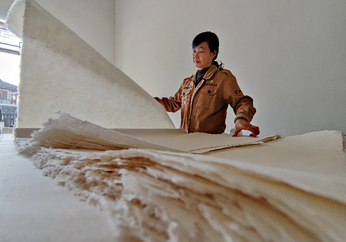 红星宣纸工作人员演示宣纸手工裁剪。