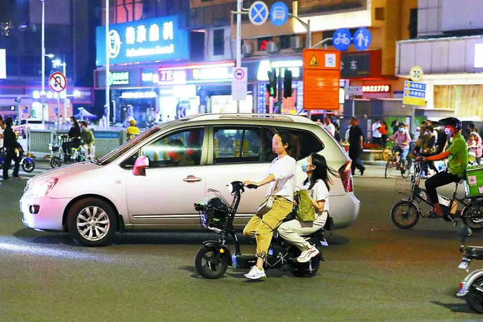 ▲傍晚下班高峰期的主道路上，市民骑着电动自行车载人行驶，两人均未戴头盔。 深圳晚报记者 张焱焱 摄