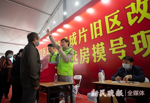 图说：工作人员报出每一位居民抽到的选房号码