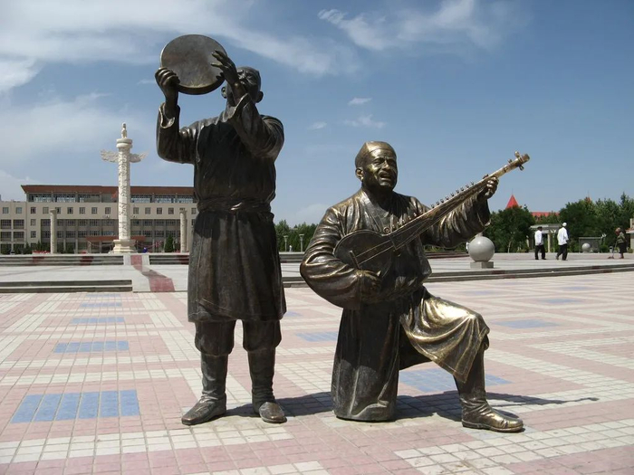 ▲麦盖提县中心广场矗立着几尊华表，歌舞铜雕塑惟妙惟肖。图片来自网络。