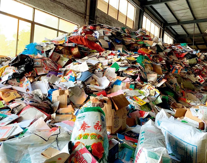 ▲ 在中部某省一再生资源公司的车间内，一座近两层楼高、如沙丘状的“教材山”异常醒目，几乎涵盖了中小学所有科目的教材，随手捡起一本初中历史教材，品相完好、干净整洁