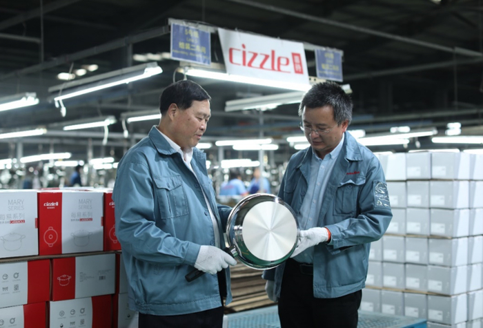 ▲冠华不锈钢创始人黄勇（左）与车间主任讨论喜时的拼多多定制款煎锅的细节。该产品与欧洲顶级厨具品牌WMF在同一条生产线上制造。（摄影：大尾）