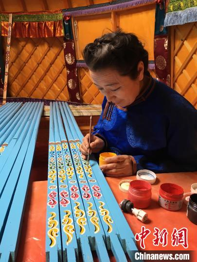 图为满其尔的妈妈正在为乌尼杆画花纹。　满其尔 摄