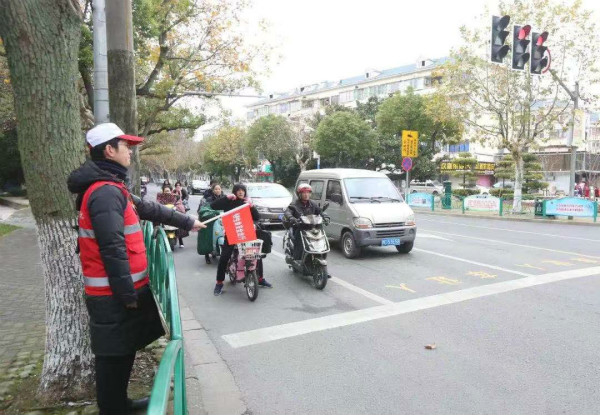 图说：志愿者帮助维护道路秩序。