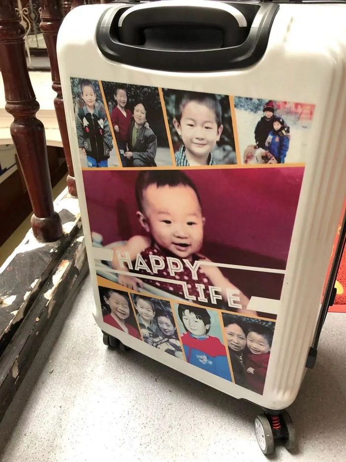 ▲何树军有一口随车带的24寸行李箱，正反面都印着李飞的照片和信息。新京报记者&nbsp; 冯雨昕 摄