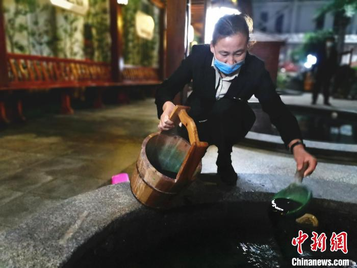 图为温泉小镇的工作人员向绿茶汤池内加入绿茶。　赵晓 摄