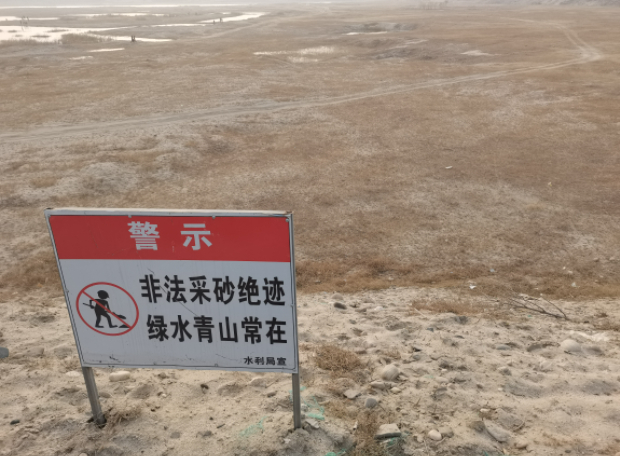  ▲水利部门在砂坑旁树起“非法采砂绝迹”的警示牌。新京报记者 李英强 摄