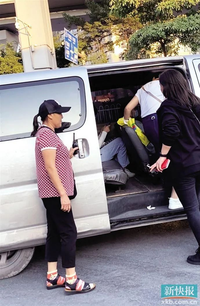 ▲女子手持对讲机，在公交站前方一边拉客一边把风。