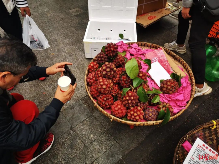 ↑见到“神奇水果”，有市民路过拍照