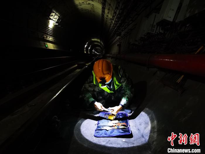 借着头上的探灯，工人从兜里掏出工具，熟练工作 王政 摄