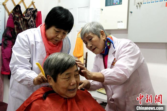 图为赵晓凤在指点志愿者为老人理发。　赵晓 摄