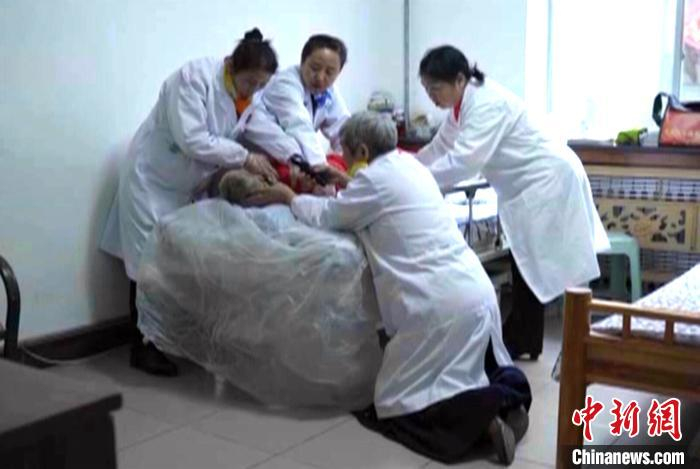 资料图：图为赵晓凤带着服务队上门为瘫痪在床的老人理发。　资料视频截图