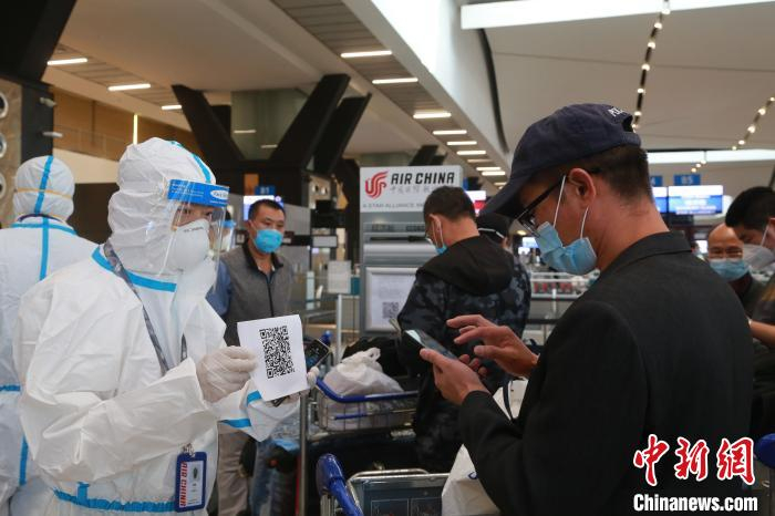 图为身着全套防护装备的国航工作人员引导旅客扫描健康码。　王曦 摄