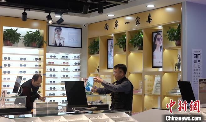 图为台胞郑景文正在店中与岳父一同忙碌，身后背景墙上写着“两岸一家亲”字样，这也是他作为一个普通人的朴实愿望。　马知远 摄