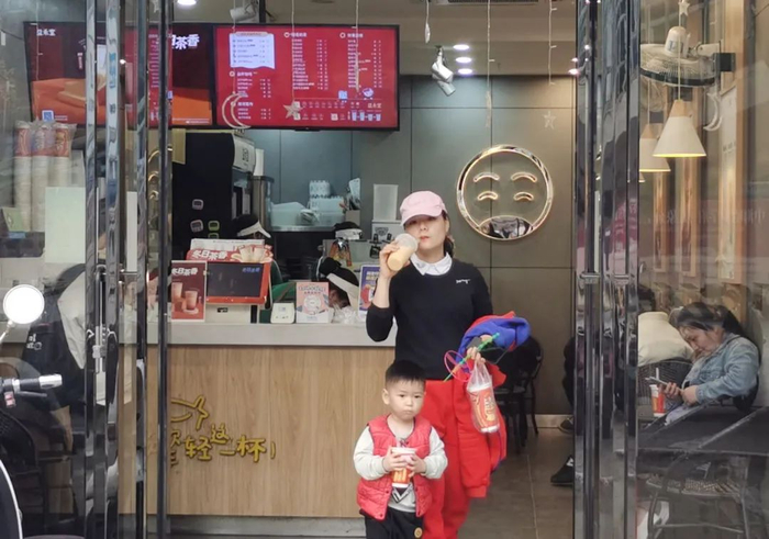 在南宁一家奶茶店前，一名女士和一名小朋友正在用塑料吸管饮用饮品 卢丽婷 摄