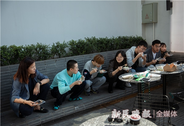图说：沈文馨（左一）的短视频制作团队蹲在露台上吃午饭 。新民晚报记者 周馨 摄（下同）