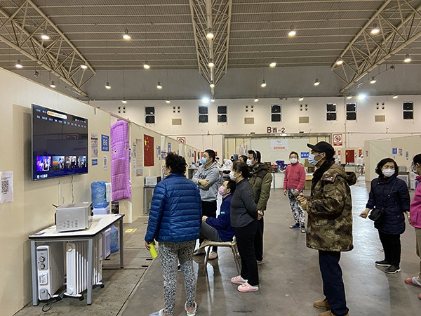 东西湖方舱B厅，一群患者正在舱内的挂壁电视点播影视剧。