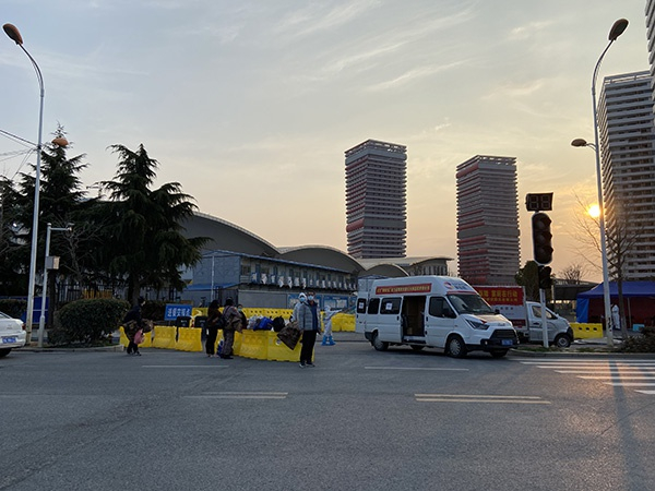 在东西湖方舱医院患者通道外等待接去康复隔离点的患者