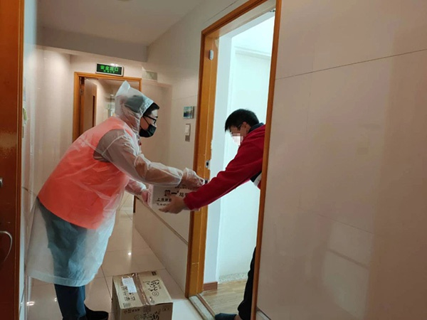 虹口区安丘居委志愿者吕旭伟（左）给日籍居家隔离人员送快递。 虹口区供图